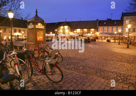 Telefono tradizionale scatola, e biciclette parcheggiate in lilla Torg, centro di Malmo, Svezia, al tramonto. Foto Stock