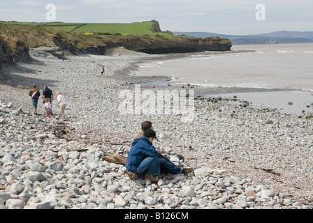 L uomo e la donna seduta sulla spiaggia di ciottoli, Kilve, Somerset, Inghilterra, Regno Unito Foto Stock