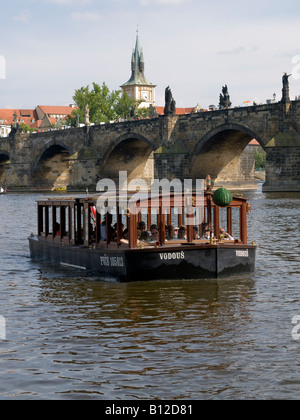 I turisti in barca il fiume Vlatva, Praga (Repubblica Ceca) con Saint Charles Bridge sul retro Foto Stock