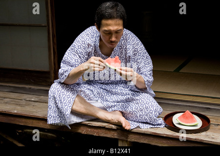 Estate in Giappone; Giapponese uomo mangiare anguria a Engawa della casa giapponese Foto Stock