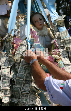 Il pinning soldi su infissi di una icona religiosa ad una parata italiana. Foto Stock