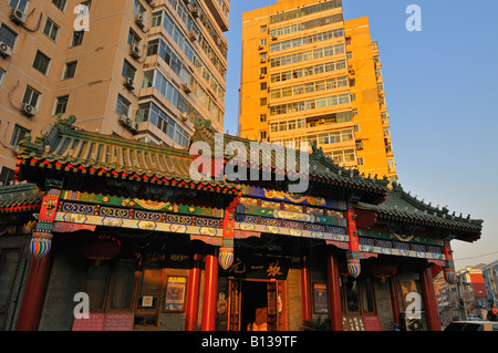 Il vecchio stile ristorante con tetto di tegole e piastrelle decorative facciata sotto moderno ed alto edificio di condomini a Beijing in Cina Foto Stock