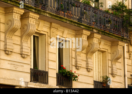 Facciata di un edificio di Parigi con balconi e finestre con fiori in primavera. Foto Stock