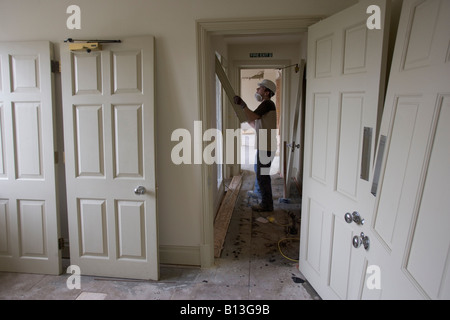 Un lavoratore edile rimuove un pezzo di stampaggio in un corridoio di un sito di demolizione. Foto Stock