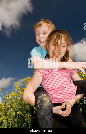 Ragazzo e ragazza scorazzare in un campo estivo Foto Stock