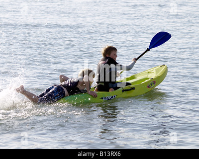 Due giovani ragazzi di indossare giubbotti, giocando su un kayak Foto Stock