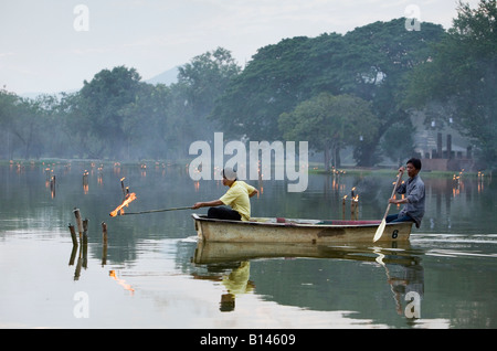 I lavoratori della luce acqua kerosene torce al Sukhothai Historical Park. Sukhothai, Sukhothai, Thailandia Foto Stock