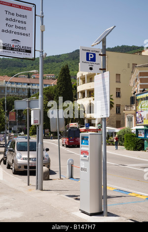 Alimentato con energia solare strada parcheggio ticket metro con piccolo pannello solare a firmare con le automobili parcheggiate su strada Opatija Croazia Europa Foto Stock