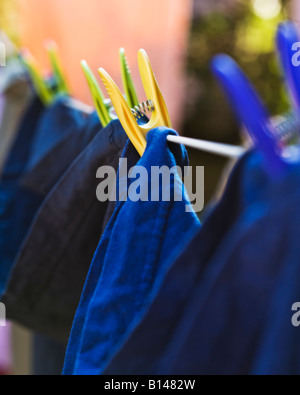 Vari capi di abbigliamento essiccazione su una linea di lavaggio tenuto da abiti colorati pioli Foto Stock