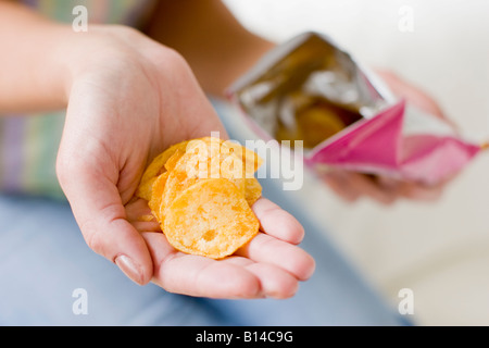 Donna che mantiene le patatine in mani Foto Stock