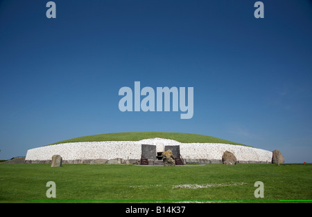 Parte anteriore del megalitico di Newgrange tumulo e pietre in piedi sotto un cielo blu , nella contea di Meath , Repubblica di Irlanda Foto Stock