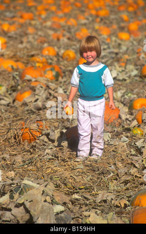 Un po' di redheaded girl sorge in un orto di zucche. Foto Stock