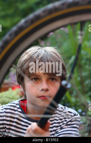 Ragazzo giovane di età superiore a dodici anni pompare fino al pneumatico su una bicicletta Foto Stock