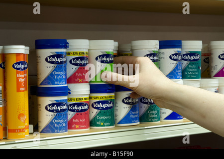 Donna di mano tenendo una Vantage vitamina pot dal ripiano in una farmacia farmacia Foto Stock