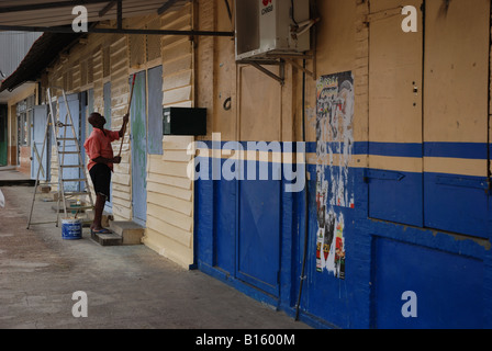 Un uomo nero vernici a fronte di una casa in legno nella Guyana francese, sud america città Foto Stock