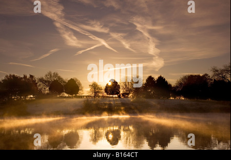 Sunrise, alba in una nebbiosa, frosty autunno inverno mattina, di nebbia che salgono dal laken a Coate Water Country Park, Wiltshire, Regno Unito Foto Stock