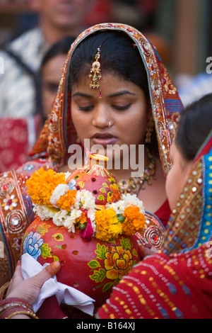 Una giovane donna di Rajasthani porta una pentola di creta con una candela come parte del festival GANGUR JOHDPUR in Rajasthan in India Foto Stock