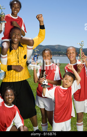 Multi-etnico bambini azienda trofei di calcio Foto Stock