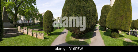 Pietra scolpita tombe e alcuni dei 99 yew alberi nel cimitero del villaggio Costwold di Painswick, Gloucestershire Foto Stock