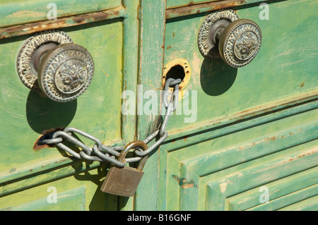 Porta manopole lucchetto e catena sul vecchio metallo verde porte close up Foto Stock