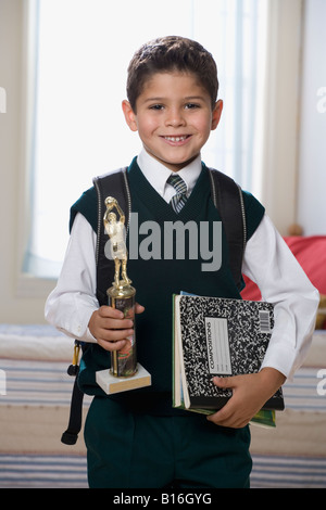 Ispanico boy holding trophy e i libri di scuola Foto Stock