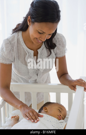 African American madre guarda il sonno del bambino Foto Stock
