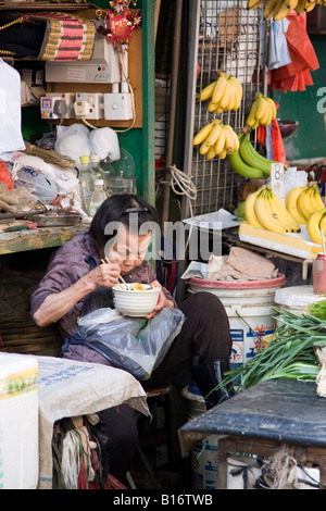 Donna cinese di mangiare il pranzo all'aperto in Kowloon Hong Kong Foto Stock