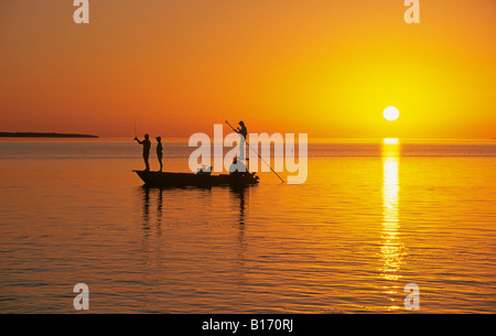 I pescatori fly cast di grandi mosche artificiali per bonefish in acque poco profonde della Florida Keys al tramonto Foto Stock