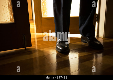 Uomo nero piedi scarpe di cuoio in piedi in un interno nel portale con pavimento in legno Foto Stock