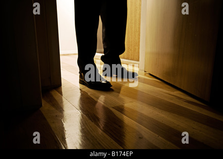 Uomo nero piedi scarpe di cuoio in piedi in un interno nel portale con pavimento in legno Foto Stock