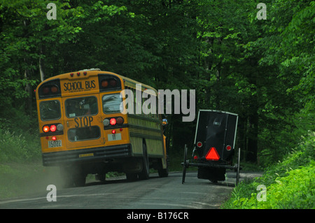 Scuola bus passando a cavallo e buggy sulla County Road Foto Stock