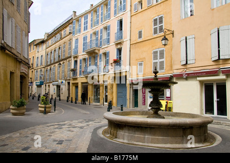 Architettura tradizionale in una strada in Aix en Provence, Francia con una fontana in primo piano e il blu del cielo. Foto Stock