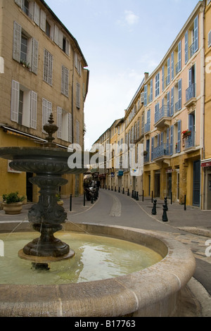 Architettura tradizionale in una strada in Aix en Provence, Francia con una fontana in primo piano e il blu del cielo. Foto Stock