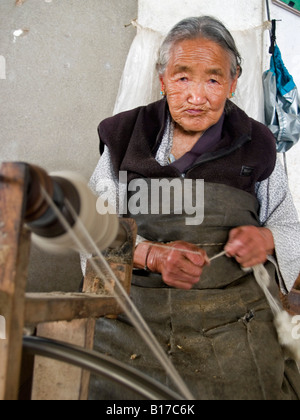 Vecchia donna tibetana la filatura della lana Foto Stock