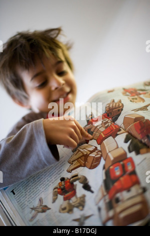 6 anno vecchio ragazzo legge un libro trasformatori ha appena uscito dalla libreria Foto Stock