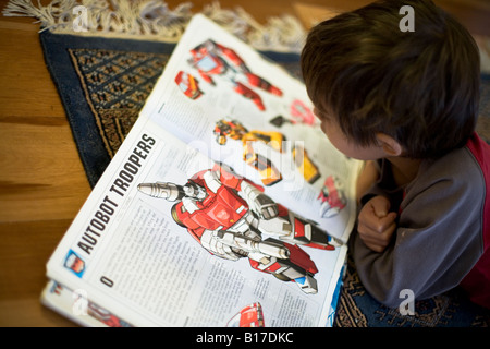 6 anno vecchio ragazzo legge un libro trasformatori ha appena uscito dalla libreria Foto Stock