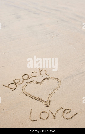 Forma di cuore e le parole 'beach amore' disegnata di sabbia su una spiaggia. Regno Unito Foto Stock