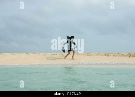 Imprenditrice ispanica camminando sulla spiaggia Foto Stock