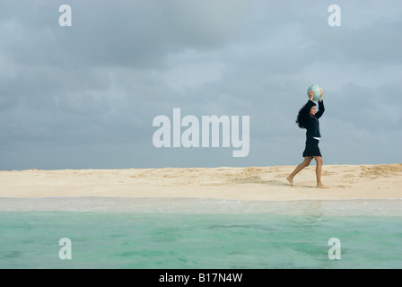 Imprenditrice ispanica tenendo palla spiaggia Foto Stock