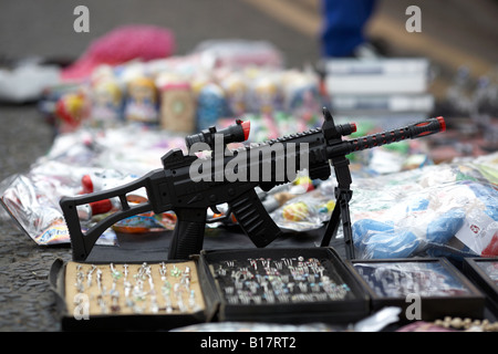 Pistola giocattolo sul display durante il Mercato di strada lungo con selezione di a buon mercato di produzione di massa di origine cinese merci Foto Stock