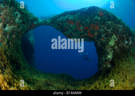 Diver sotto arco roccioso Triscavac Bay Susac isola mare adriatico Croazia Foto Stock