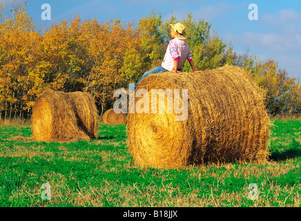 17 anno vecchia ragazza sul rotolo di erba medica in autunno, vicino a Winnipeg, Manitoba, Canada Foto Stock