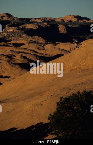 Un ciclista in sella verso il basso di un divertente e grippy pendenza di arenaria in Moab, Utah, Stati Uniti. Foto Stock