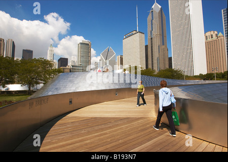 Parchi Chicago in Illinois due donne camminando sul Ponte di BP Frank Gehry design in Millennium Park skyline in acciaio inox curve Foto Stock