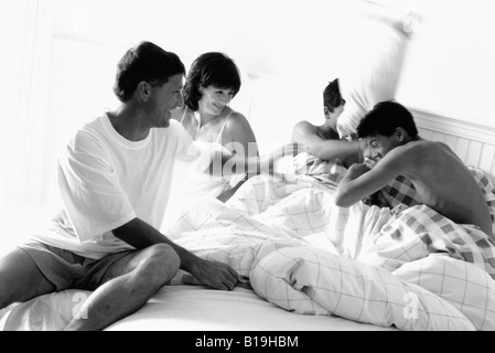 Famiglia avente pillow fight in letto, in bianco e nero Foto Stock