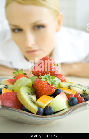 Donna che guarda al piatto di insalata di frutta Foto Stock