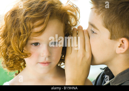 Ragazzo whispering nella ragazza l orecchio, close-up Foto Stock