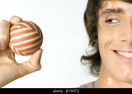 Giovane uomo tenendo palla, sorridente, vista ritagliata Foto Stock