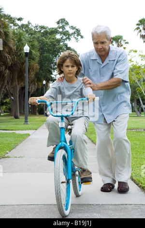 Nonno insegnamento ragazzo a guidare la bicicletta a piena lunghezza Foto Stock