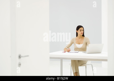 Ufficio femmina lavoratore seduto alla scrivania, utilizzando il computer portatile Foto Stock